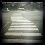 Ein Zebrastreifenschlängelt sich gewunden über einen großen Parkplatz auf ein Schild zu mit der Aufschrift "Sapeurs Pompiers"