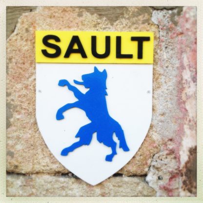 Silhouette eines Fuchses oder eines ähnlichen Tiers, blau, im Profil, aufrecht stehend, rausgestreckte Zunge unter dem Schriftzug "SAULT".