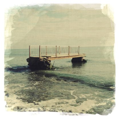 Im seichten Wasser an einem Meeresstrand sind die Überreste eines Fußgängerstegs zu erkennen, ein etwa vier Meter langes Etwas.