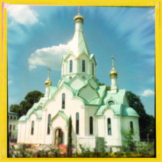 In einem gelben, quadratischen Rahmen erglänzt eine fast weiße Kirche mit goldenen Kuppeln, die aussieht wie ein Märchenschloss