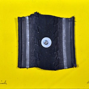 Auf einem gelben Bildträger ist ein Reifenstück, quadratisch mit derbem gesägten Rand aufgeschraubt mittels Linsenkopfschraube und Unterlagsscheibe mittig.