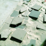 Wie schlecht gepflastert wirkt dieses Bauschuttensemble von teils gebrochenen Pflastersteinen auf einem Sanduntergrund.