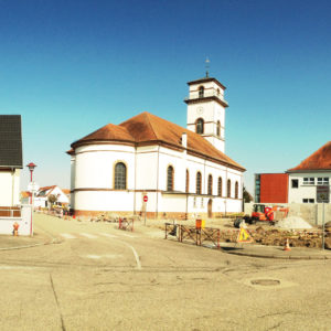 Eine schlichte, weiße Kirche mit rotem Dach und quadratischem Turm.