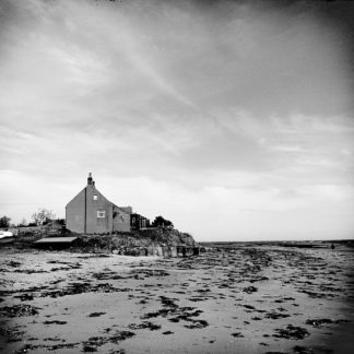 Schwatz weiß Bild eines einsamen, schlichten Hauses an einem Strand bei Ebbe.