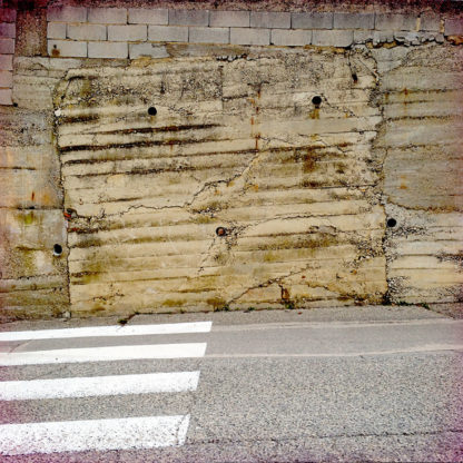 Zebrastreifen führt auf eine notdürftig gemauerte, ockerfarbene Wand zu.