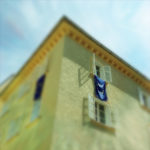 Froschperspektive auf ein Stadthaus, aus dessen Fenster eine Europaflagge hängt.