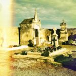 Ein Fehlfarbenstreifen wie von Lichtverblitztem altem Farbfilm links begleitet das Auge auf einen französischen Friedhof. Im Zentrum eine große Gruft vor Friedhofsmauer und ein kleineres Grab mit vielen Sogenannten Souvenirs.