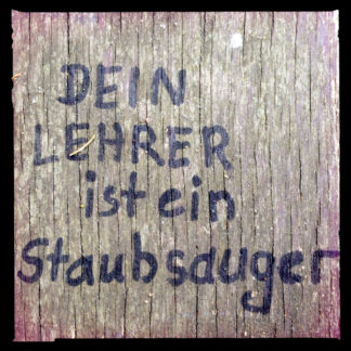 Mit Edding geschrieben auf Holzbank: Dein Lehrer ist ein Staubsauger. Schwarz umrandet.