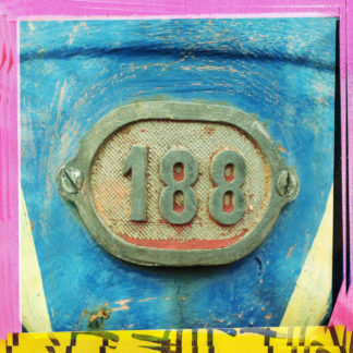 Bunter Rahmen gelb und rosa um eine Zahl 188, die als Alurelieffplatte an einem blauen Hintergrund verschraubt ist.