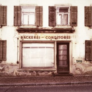 Geschlossener alter Einkaufsladen, Bäckerei - Conditorei. Heruntergelassener Fensterladen vor Schaufenster neben uralter Tür.