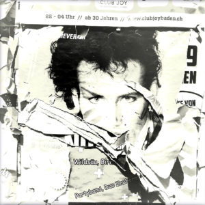 Schwarz-weiß-Foto einer zerfetzten Plakatwand, deren Hauptmotiv ein Gesicht einer Art Popstar ist. Die Frisur könnte aus der Zeit Ende 1980er Jahre stammen.