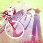 Lenker und Vorderrad eines Reiserads, neben dem sich der Fotograf als rötlich fehlfarbener Schatten abbildet.
