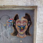 Aus dem Mund eines etwas unproportionalen Portraits einer Frau fliegt ein schillernder Paradiesvogel. Das Graffito ist in einem zugemauerten Fenster an einer Wand mit Kreide gemalt.