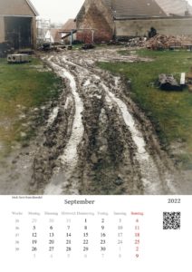 Völlig zerfahrene Wiese vor bäuerlichem Anwesen, auf dem einiges Gerümpel liegt über dem Kalendarium September.