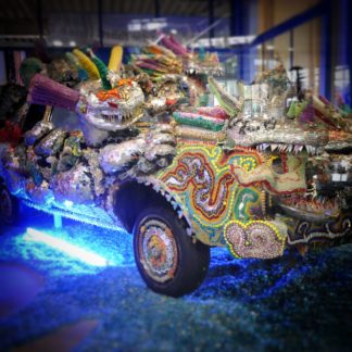 Buntes, reichlich verziertes Auto bläulich ausgeleuchtet in einem Museum