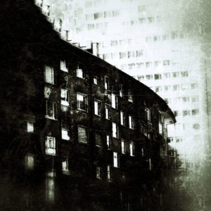 Düster wirkendes Schwarzweißbild einer sich krümmenden, mehr als die Bildmitte überziehenden Stadtgebäudes mit vielen hellen Fenstern, stilisiert und entfremdet unter Grunge-Effekten.