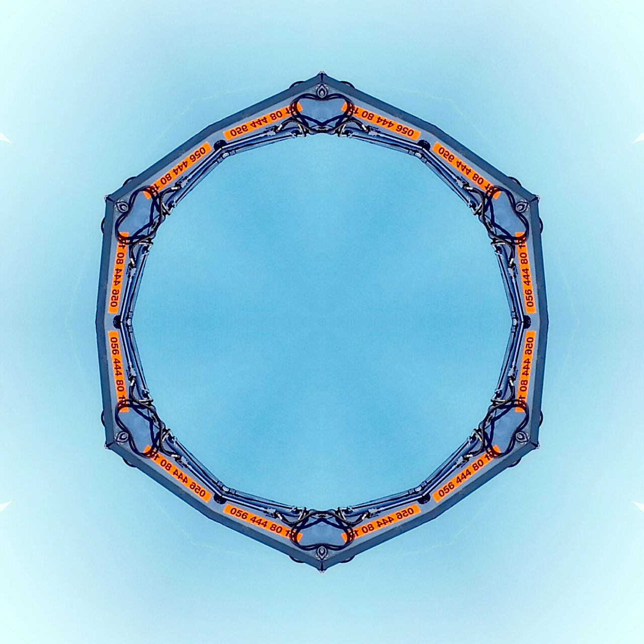 Strukturierter, rötlicher Ring mit bläulichen Eckpunkten, der im Innern rund ist und außen zu einem Sechseck tendiert auf hellblauem Hintergrund.