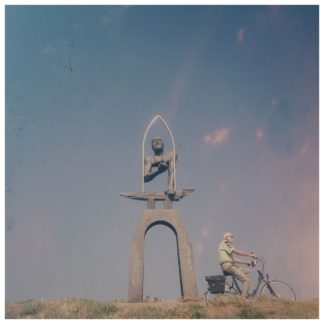 Retrobild eines Radlers, der an einer bastrakten menschlichen Skulptur vorbei radelt. Underfootaufnahme einen Deich hinauf