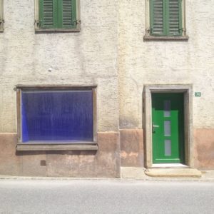 Hausfassade mit blauem Fenster und grüner Tür